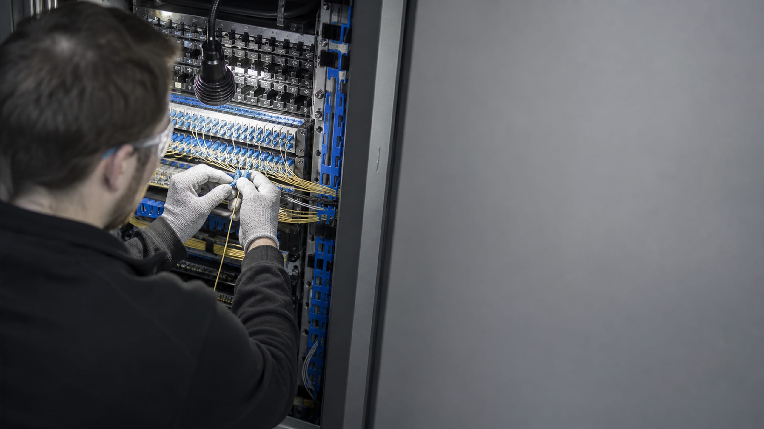 A cabling technician dressing a bundle of fiber into a high-density patch panel.